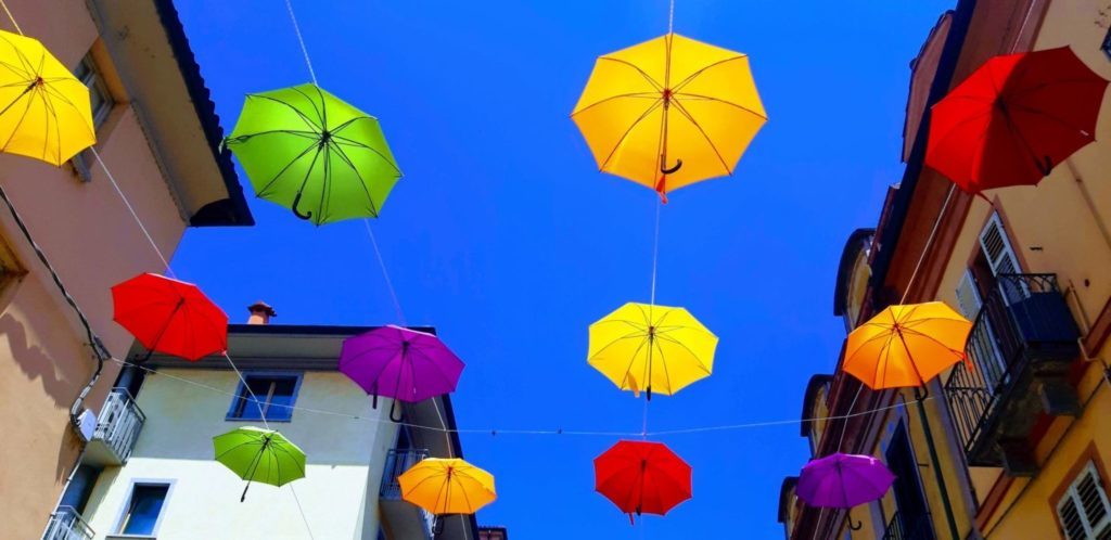 The sky above Monferrato St. full of colored umbrellas
